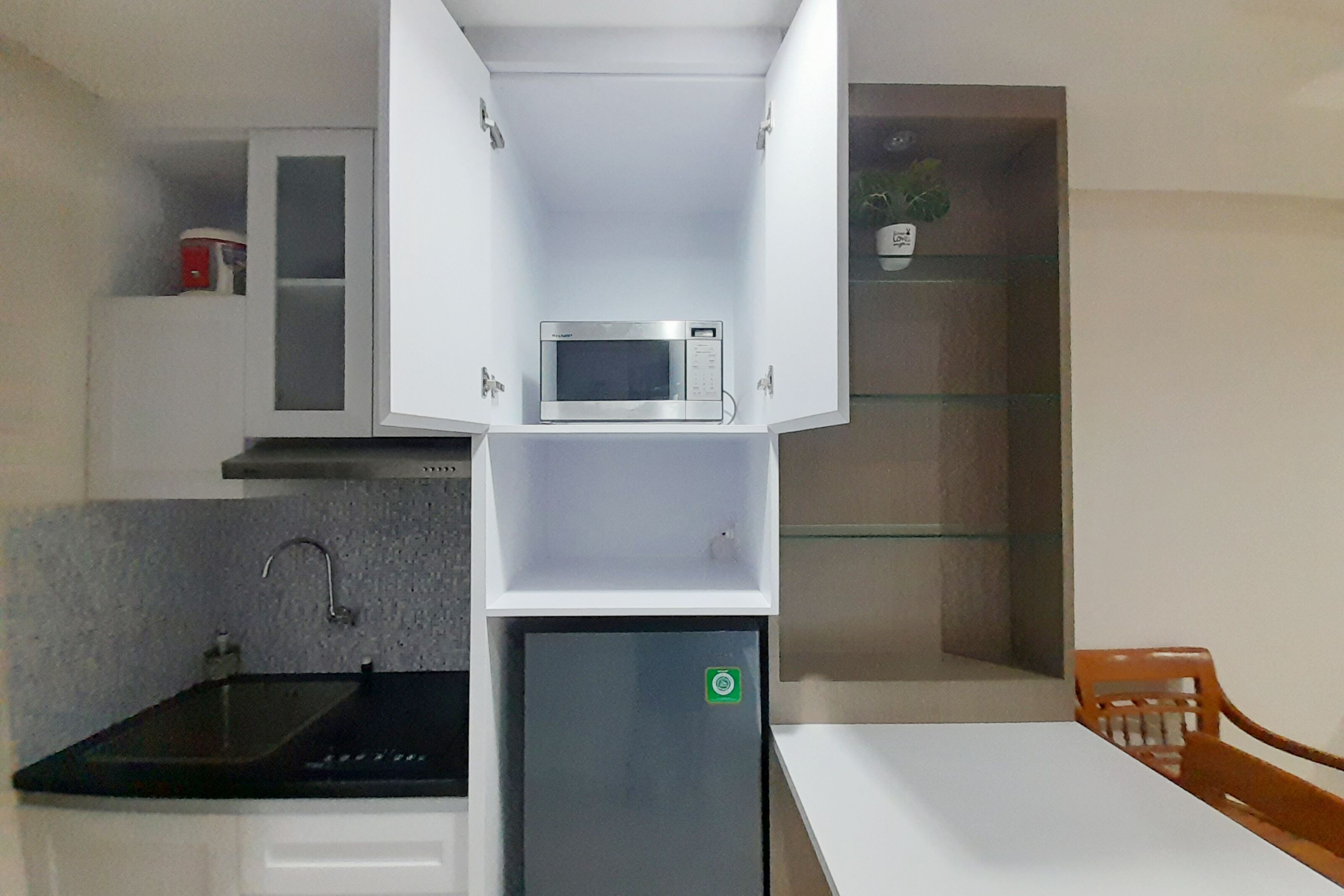 A compact kitchen with a microwave, a small refrigerator, a sink, and a dining area with a table and chairs.
