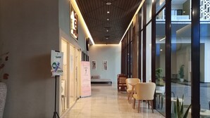 A hotel lobby with a modern design, featuring a reception desk, seating area, and large windows. - Cozy Studio Room At Patraland Amarta Apartment (Ngaglik)