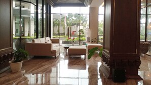 A spacious lobby with a marble floor, a sofa, a coffee table, and potted plants. - Cozy Studio Room At Patraland Amarta Apartment (Ngaglik)
