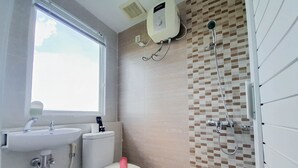 Une salle de bain avec une fenêtre, un lavabo, des toilettes et une douche.