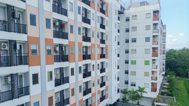 Un immeuble résidentiel à plusieurs étages, doté de balcons, de climatiseurs et d’une piscine.