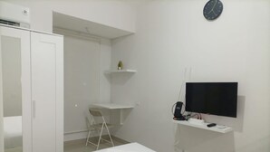Une chambre d’hôtel moderne équipée d’un lit, d’un bureau, d’une chaise, d’une télévision et d’une armoire.