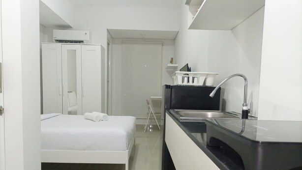 Une chambre d’hôtel moderne équipée d’un lit, d’une petite kitchenette et d’une salle de bain.