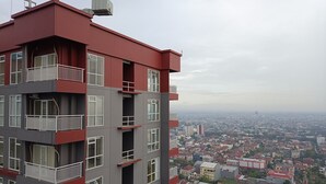 A multi-story building with balconies and large windows, overlooking a densely populated urban area. - Cozy And High Floor Studio Room At Vida View Makassar Apartment (Makassar)