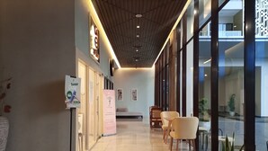 A modern hotel lobby with a wooden ceiling, large windows, and a reception desk.