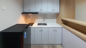 A compact kitchen with white cabinets, a black countertop, and a built-in sink.