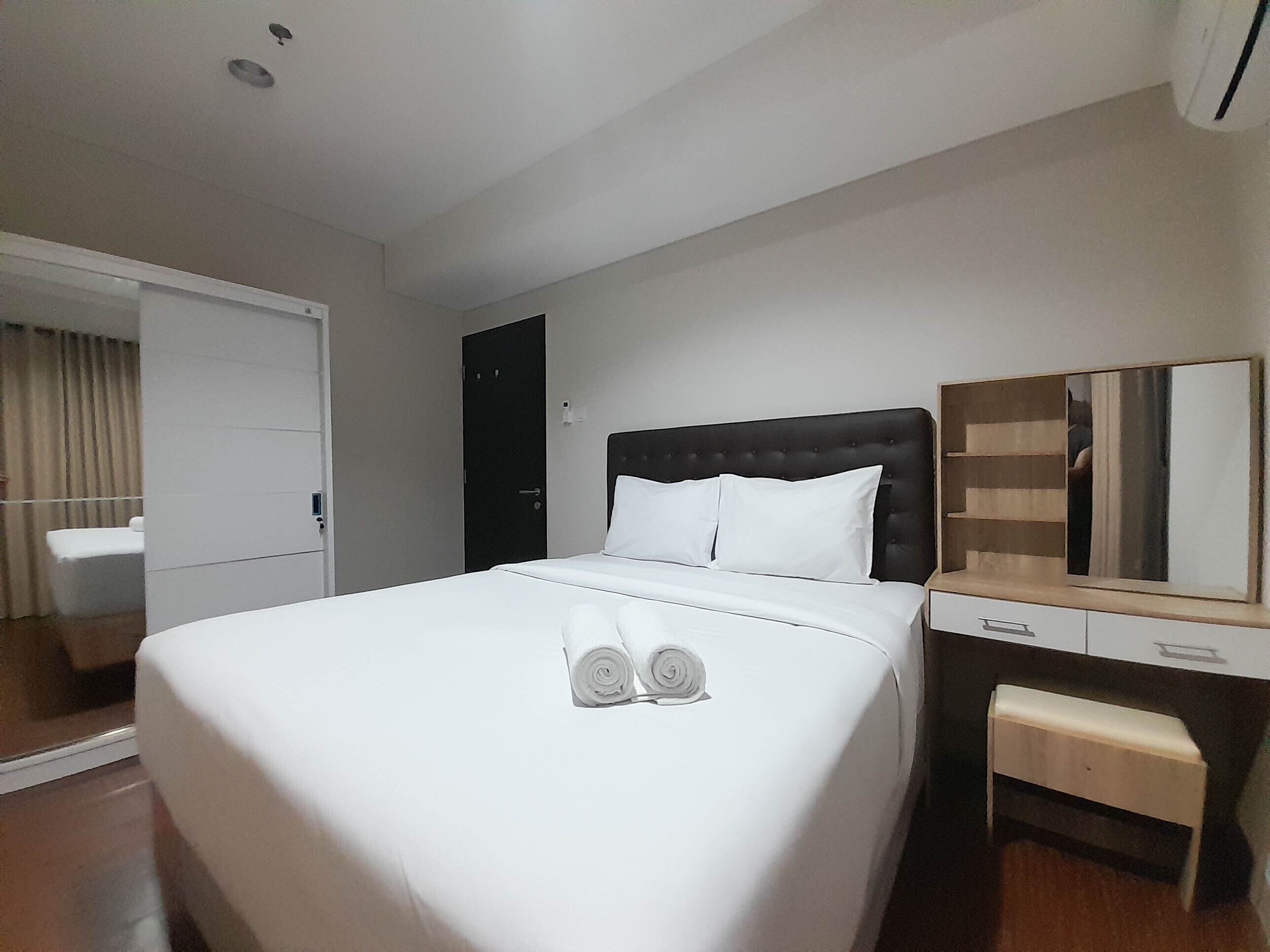 A hotel room with a large bed, a bedside table, a mirror, and a wardrobe.