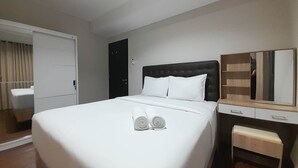 A hotel room with a large bed, a bedside table, a mirror, and a wardrobe.