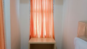 Une petite pièce avec un bureau en bois et un tabouret jaune.
