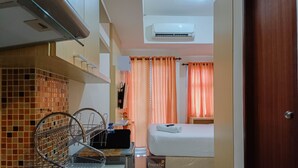 Une chambre d’hôtel avec un lit, une petite table, une chaise, une étagère avec des articles de toilette et une fenêtre avec des rideaux.