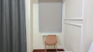 Ein Zimmer mit Fenster, Stuhl und weißem Tisch.