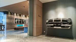 Eine moderne Lobby mit Holzboden, einem Wandbild mit Kakteen und einem Modell eines Oldtimers.