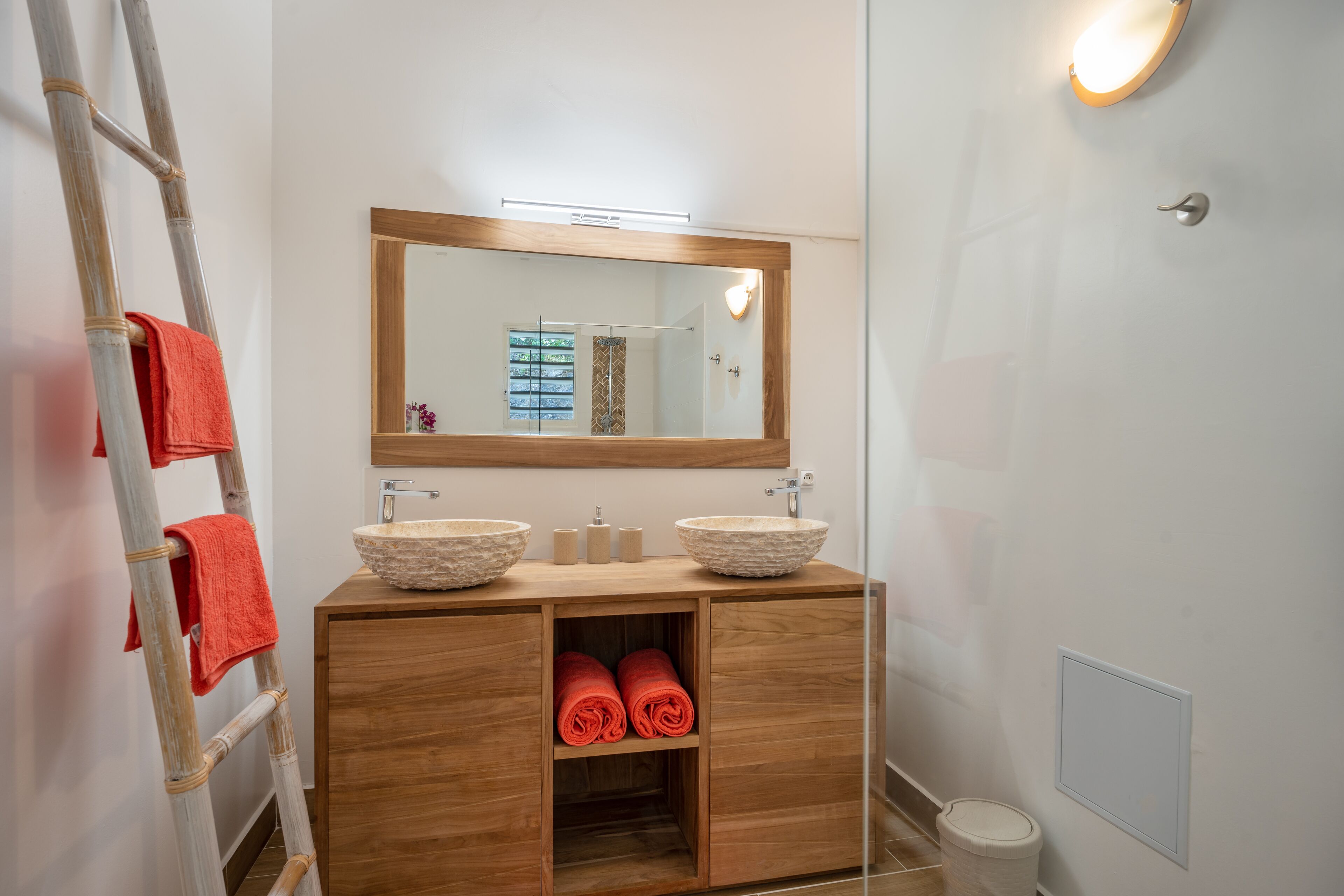 A bathroom with a wooden vanity, two vessel sinks, a mirror, and a towel rack.