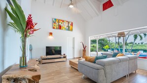 Ein modernes Wohnzimmer mit grauem Sofa, Holztisch und Flachbildfernseher.