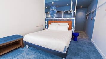 A modern bedroom with a bed, a bench, and a blue carpet.