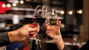 Una botella de vino, dos copas de vino y un plato de comida sobre una mesa.