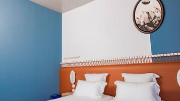 Ein Hotelzimmer mit Bett, weißen Kissen, einem Kopfende mit ungewöhnlichem Design und einem Wandbild.