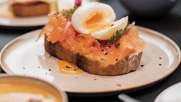 A breakfast setting with a plate of smoked salmon on toast, a poached egg, and garnishes.