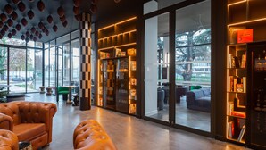 Un interior moderno con sofás de cuero, una puerta de cristal que da al exterior y una estantería con libros.