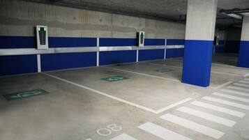 Een parkeergarage met blauwe en witte pilaren, groene parkeerplaatsen voor gehandicapten en witte parkeerlijnen.