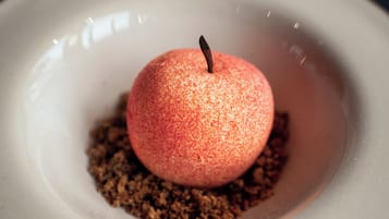 A dessert on a white plate with a textured surface and a central apple-like fruit.