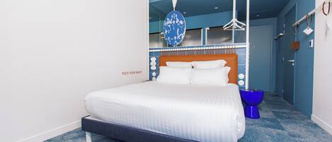 Ein modernes Hotelzimmer mit einem großen Bett, einer blauen und weißen Wand und einem blauen Teppich.