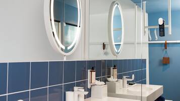 A modern bathroom with two sinks, a large mirror, and blue-tiled walls.