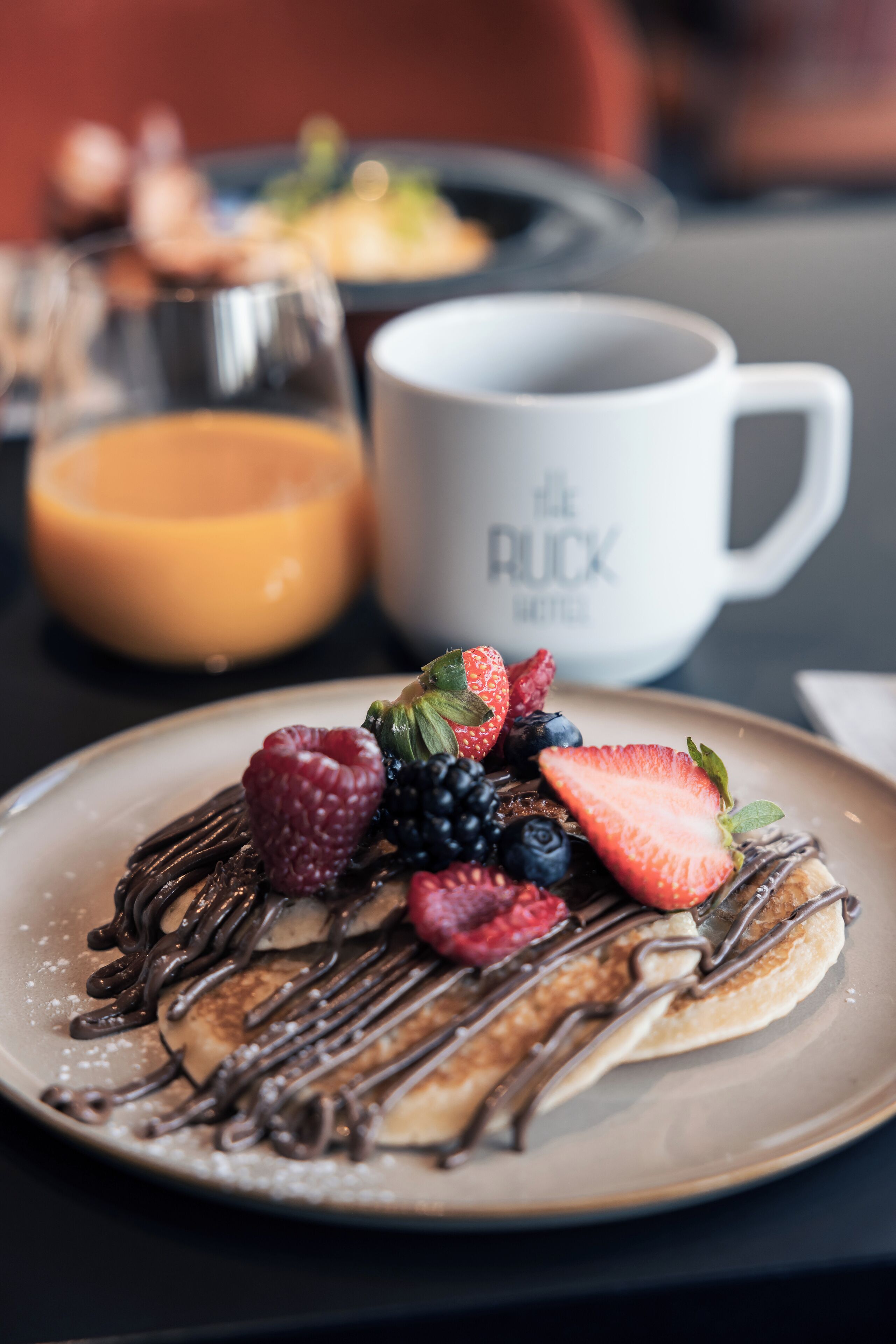 A breakfast plate with pancakes, chocolate drizzle, and fresh berries.