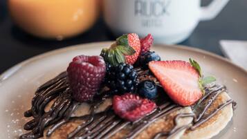 A breakfast plate with pancakes, chocolate drizzle, and fresh berries.