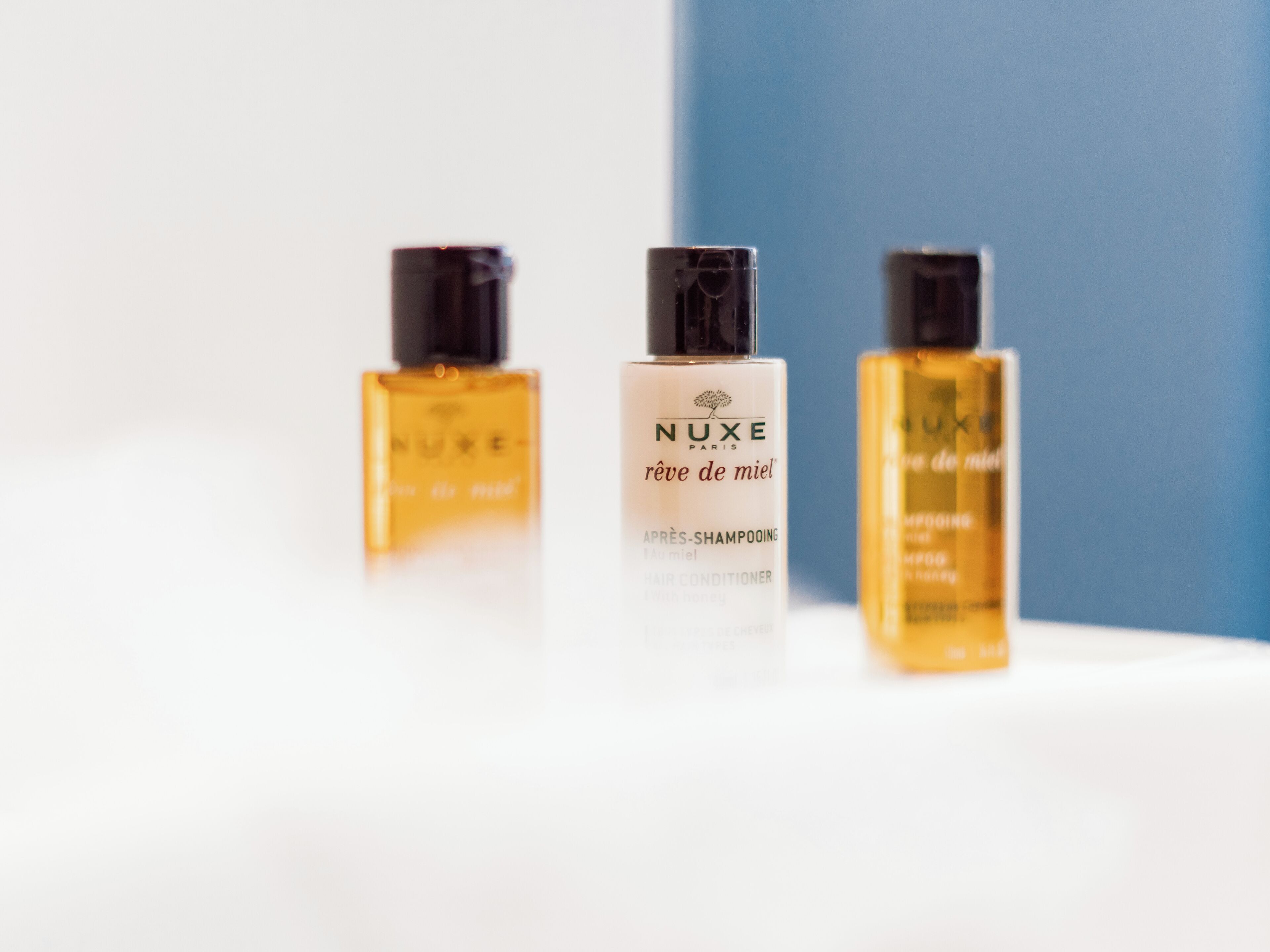 Three bottles of Nuxe Paris hair care products on a white surface.