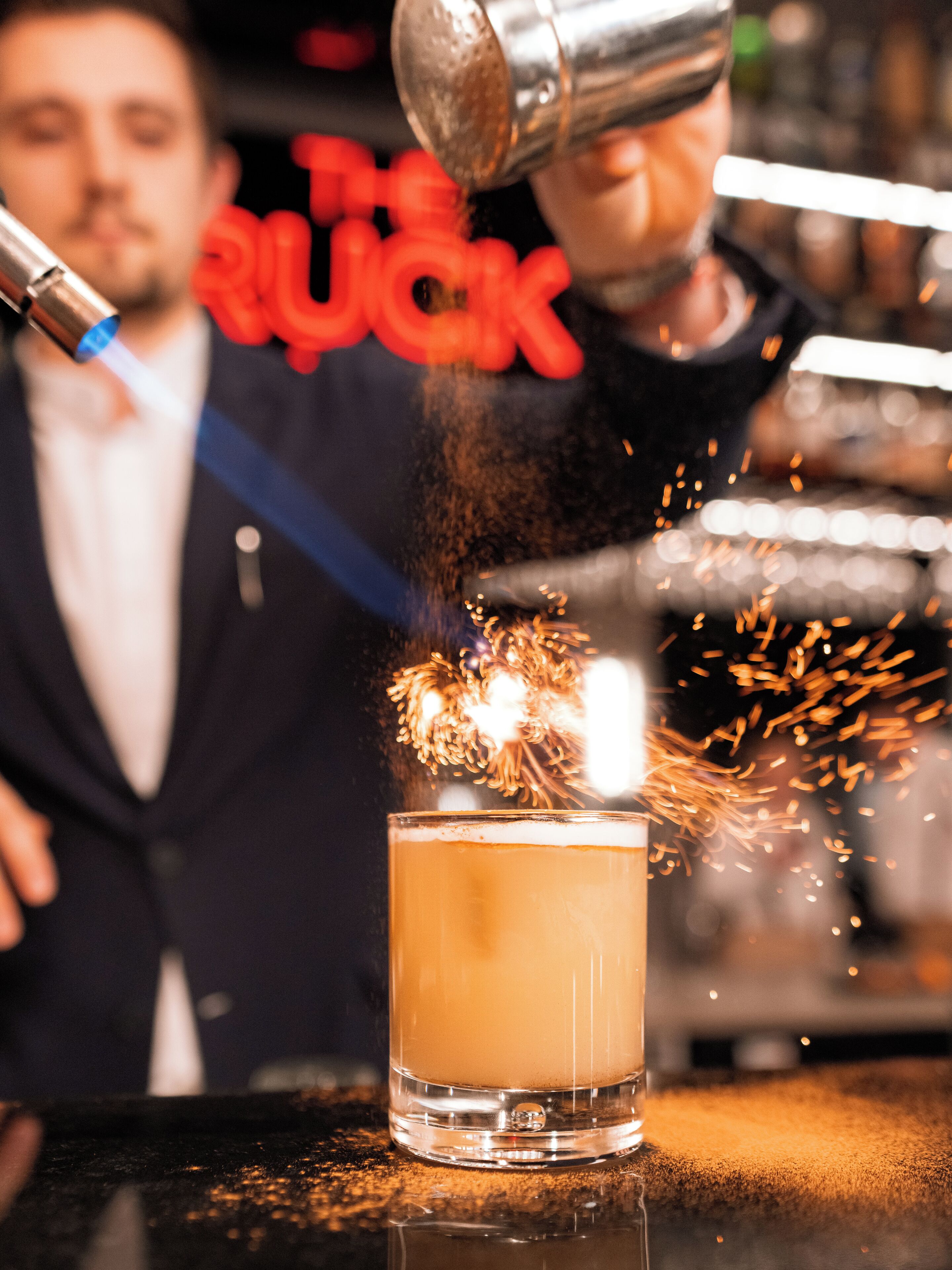Un bartender sirviendo una bebida con un serpentín, creando un efecto visual.