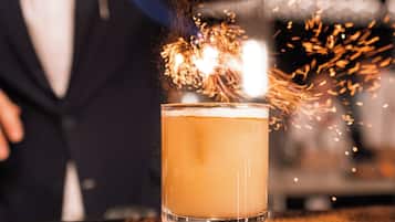 Een bartender schenkt een drankje met een fakkel, wat een visueel effect creëert.