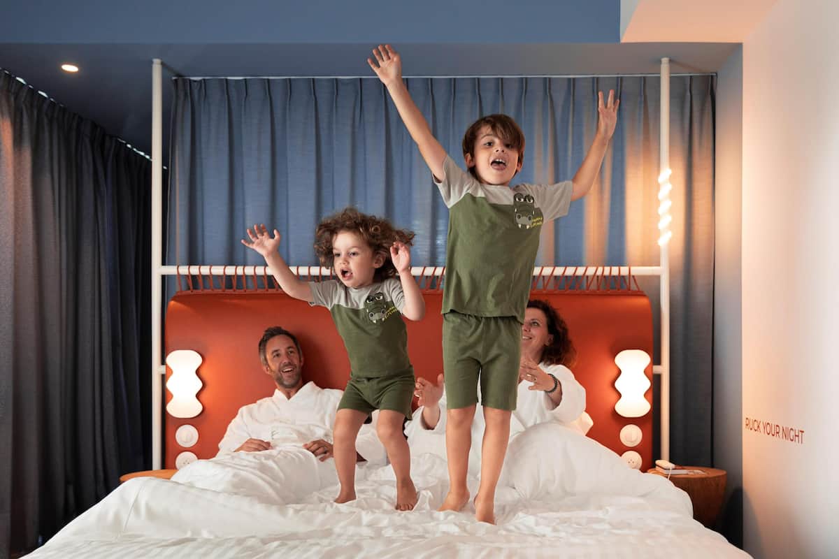 Een hotelkamer met een bed, nachtkastje en een wand met een lamp.