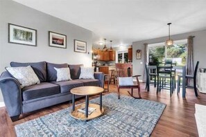 A modern living room with a sofa, coffee table, and dining area.