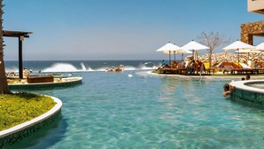 A clear blue pool with a water fountain, surrounded by lounge chairs and umbrellas, overlooking the ocean. - Grand Solmar Lands End Ocean front condo in a private gated area, Stunning views (Cabo San Lucas)