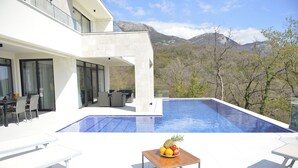 Ein modernes Haus mit Swimmingpool, Sitzgelegenheit im Freien und Blick auf die Berge.