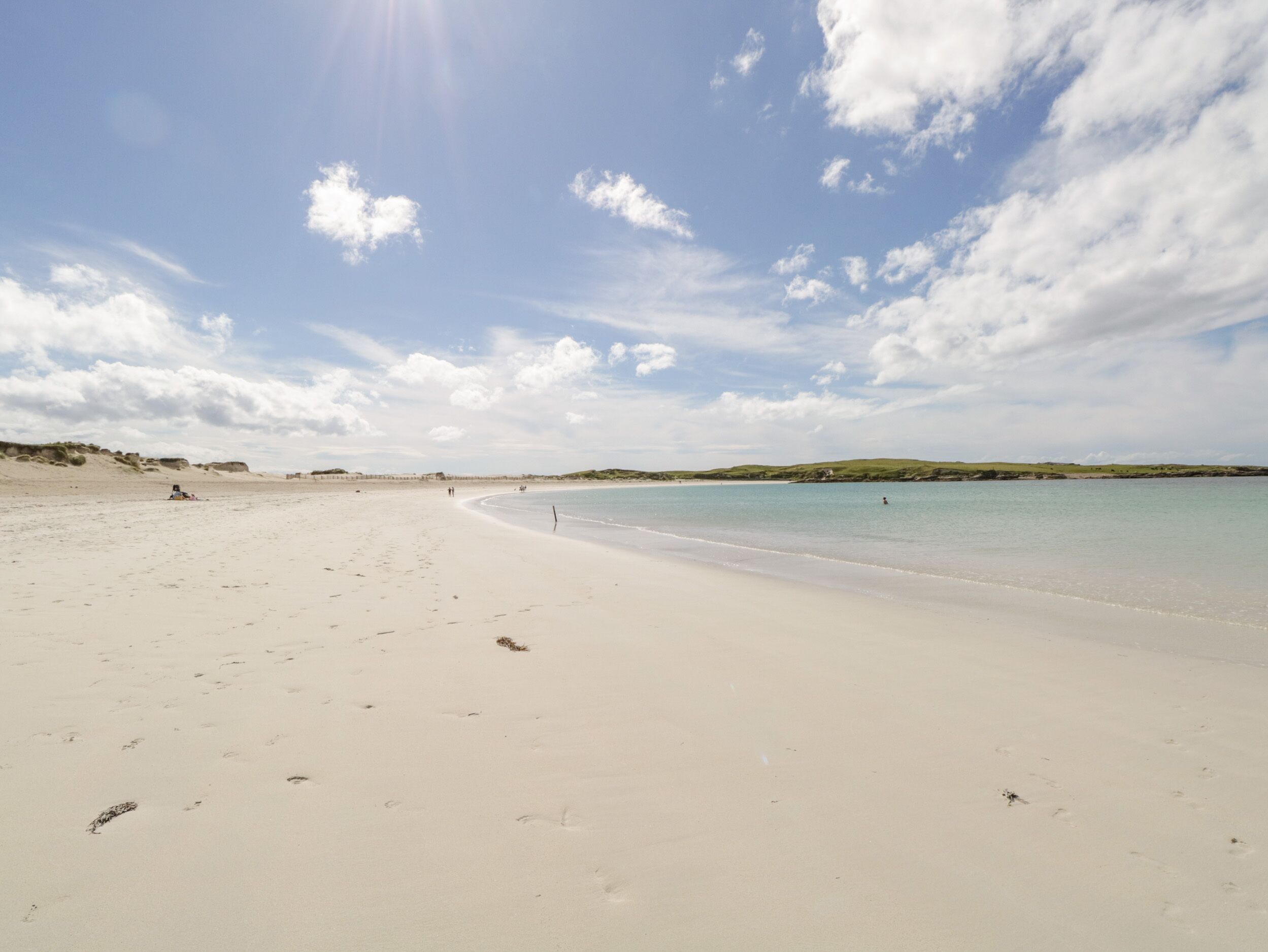 A wide sandy beach with gentle waves and a clear sky.