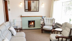 A living room with a fireplace, two patterned sofas, and two armchairs.