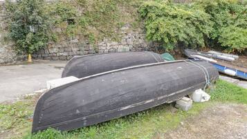 Twee grote zwarte boten afgemeerd op een gazon met een stenen muur en gebouwen op de achtergrond.