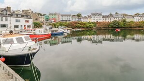 A harbor with boats docked, buildings along the shore, and a calm water body reflecting the sky.