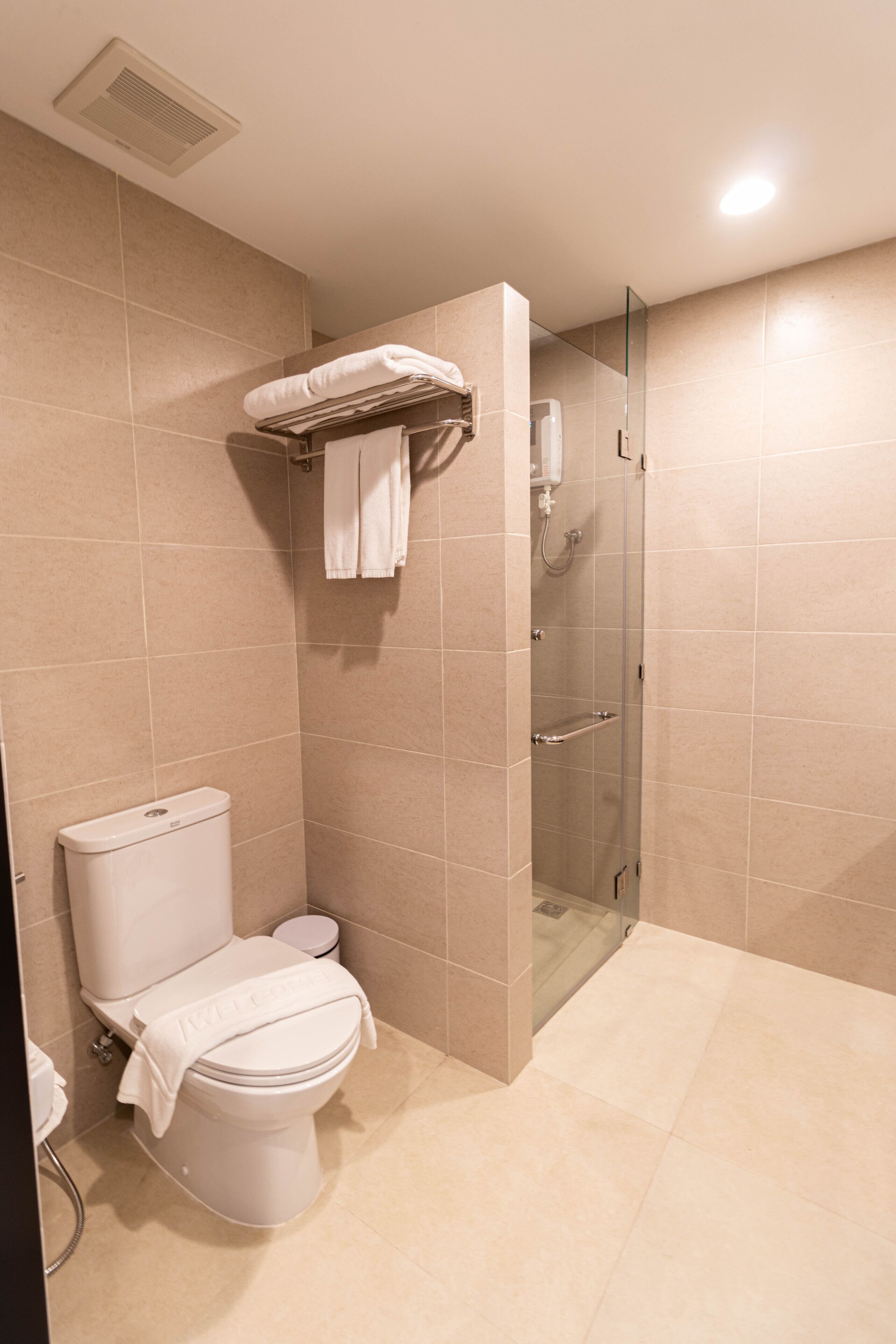 A modern bathroom with a toilet, shower, and glass door.