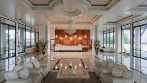 A spacious lobby with a reception desk, seating area, and large windows offering views of the outdoors. - Sea Sand Sun Hua Hin by JC Kevin Hotel & Resort (Cha-am)