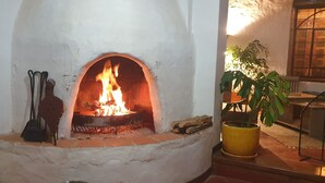 A fireplace with a fire, a potted plant, and a metal chair. - Ecolodge and Retreat "Casa de Colibri (Cajamarca)