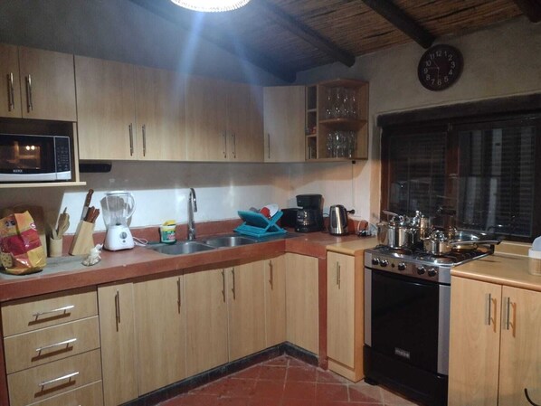 A kitchen with wooden cabinets, a microwave, a sink, a stove, and various kitchen appliances.