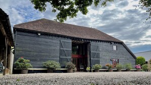 A rustic barn-style building with a gravel driveway and potted plants.
