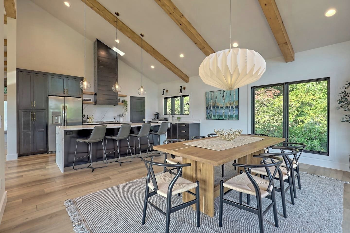 Een moderne keuken met donkere kastjes, een houten eiland en hangende lampen.