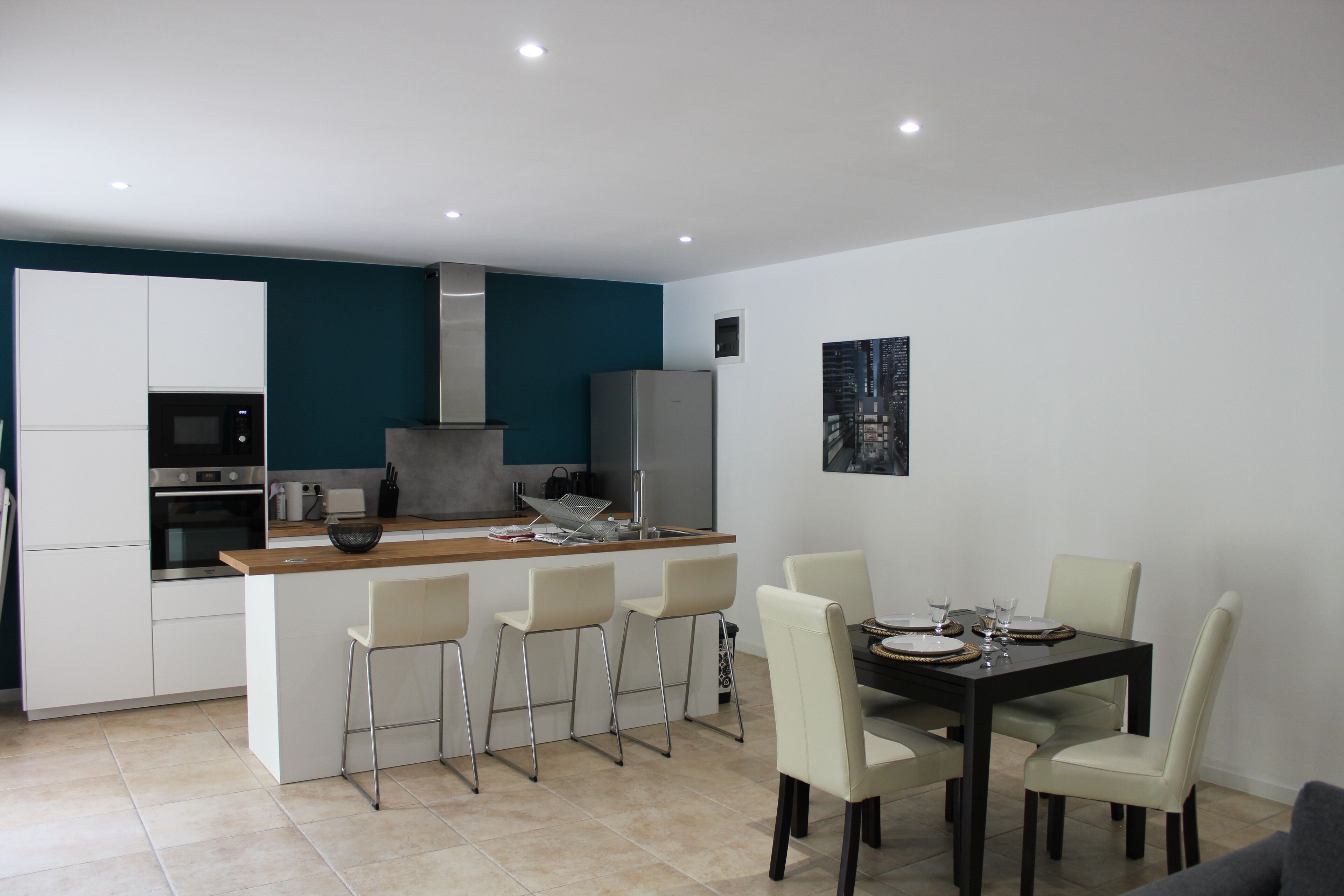Une cuisine moderne dotée d’un îlot central, de tabourets de bar et d’une table à manger avec des chaises.