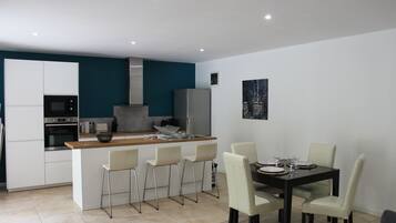 Une cuisine moderne dotée d’un îlot central, de tabourets de bar et d’une table à manger avec des chaises.