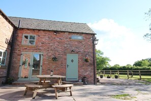 A brick building with two doors, a window, and a hanging flower basket. - The Hoglets 1 - 2 bedroom Property (Cheshire)