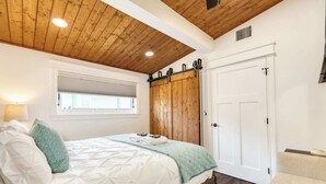 Un dormitorio con cama, ventana, puerta corrediza tipo establo y una silla.
